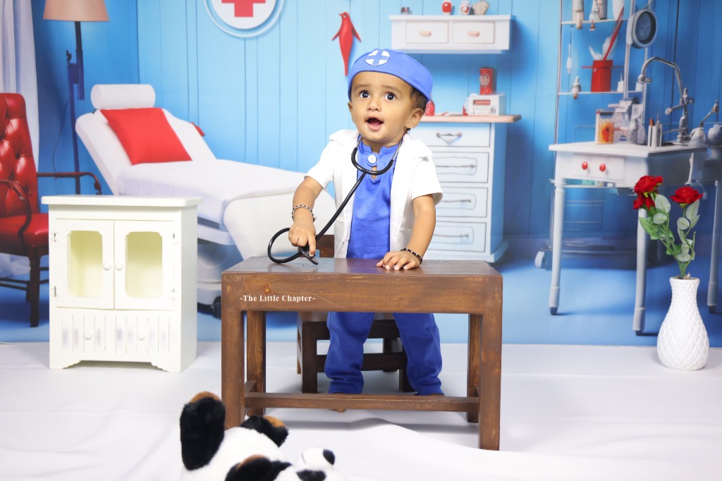 Baby doctor in blue surgical scrubs and white coat at medical clinic desk with stethoscope